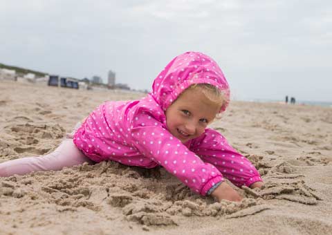 Kind am Strand im Sand spielend 